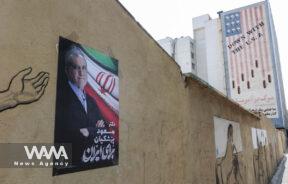 A poster of presidential candidate Masoud Pezeshkian is displayed near an anti-U.S. mural on a street in Tehran