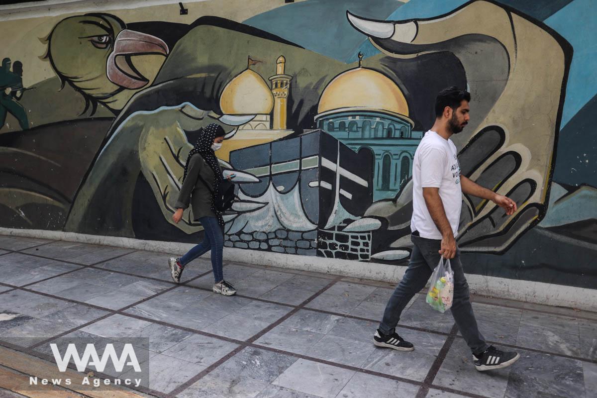 Iranians walk past an anti-Israel mural on a street in Tehran, Iran July 31, 2024. Majid Asgaripour/WANA (West Asia News Agency)