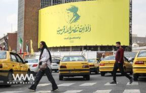 People walk past a billboard with a picture of the late Lebanon's Hezbollah leader, Sayyed Hassan Nasrallah, in a street in Tehran