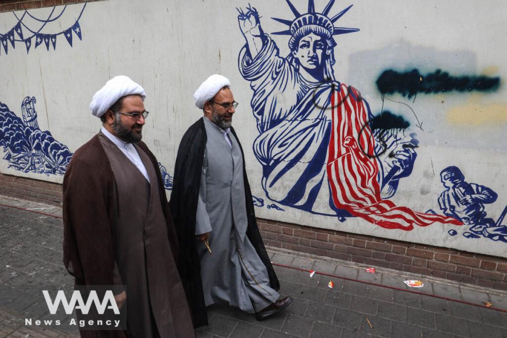 Iranian clerics pass in front of an anti-U.S. mural during the 45th anniversary of the U.S. expulsion from Iran